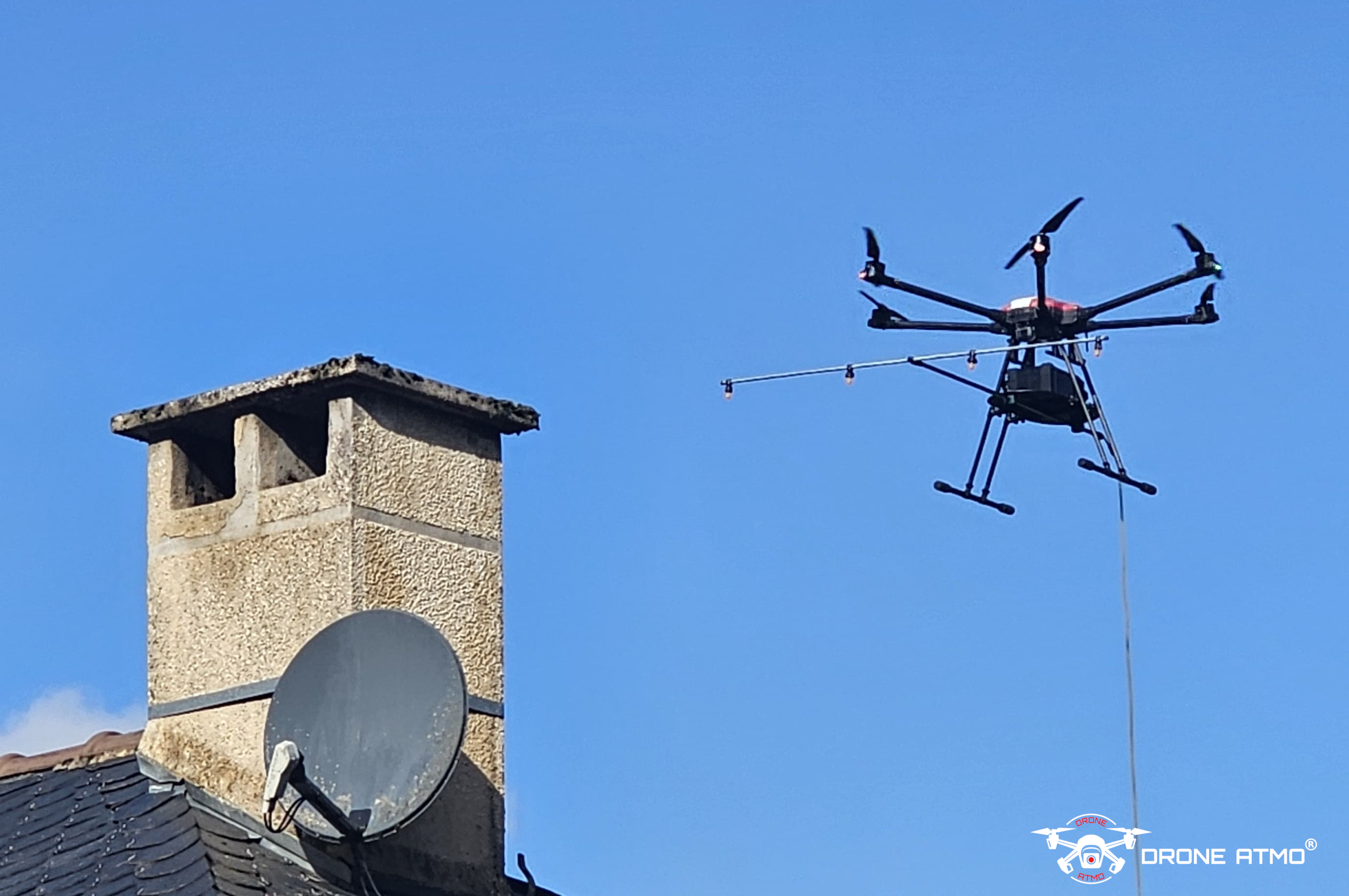 le drone spray L en survol de toiture lors d'un chantier de pulvérisation anti mousse (nettoyage de toiture)